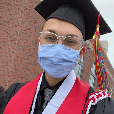 Lee in facemask and graduation cap and gown