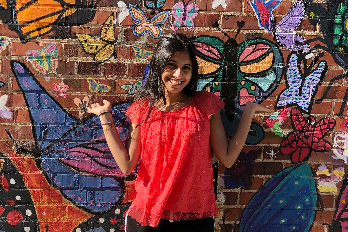 Riha in front of a brick wall with art on it