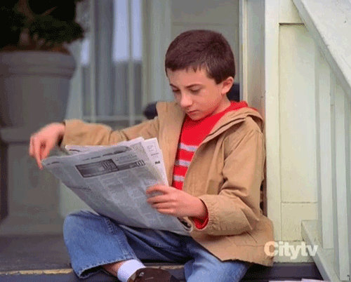 Brother from Malcom in the Middle reading newspaper raising finger to indicate one more minute.